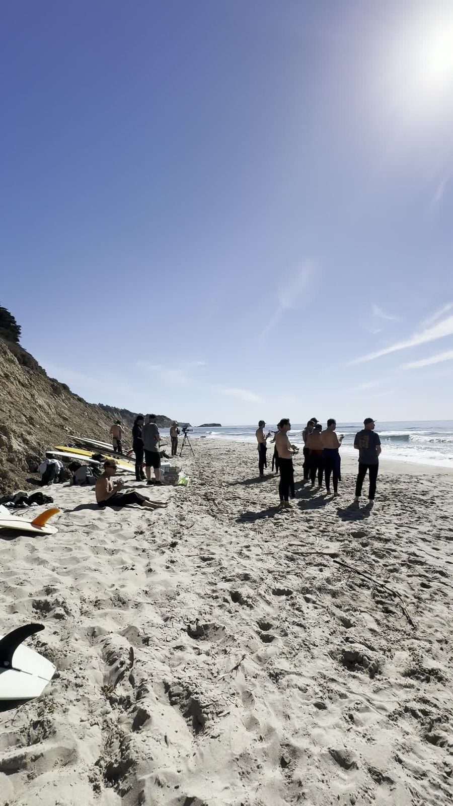 A group gathered on a sunny beach with surfboards